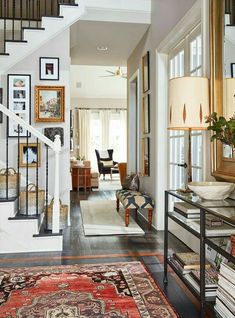 an entry way with stairs, rugs and pictures on the wall in front of it