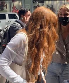 two women with masks on talking to each other in front of a storefront window