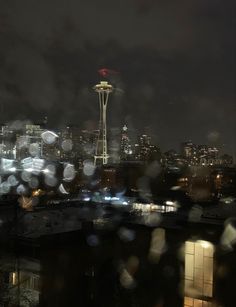 the seattle skyline is seen through raindrops on a cloudy night in this photo