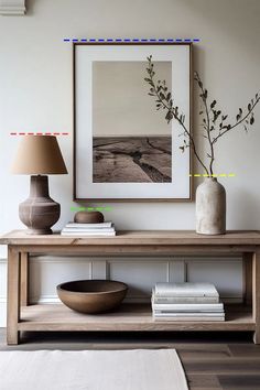 a table with two vases on it next to a lamp and pictures hanging on the wall