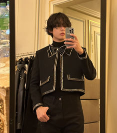 a man taking a selfie in front of a mirror wearing a black suit and bow tie