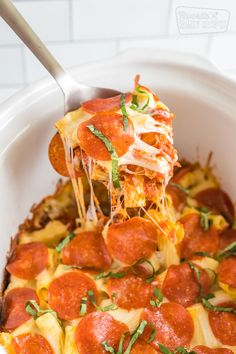 a slice of pepperoni pizza being lifted from a casserole dish