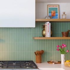 a stove top oven sitting inside of a kitchen next to a shelf filled with books