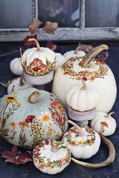 white pumpkins decorated with flowers and leaves on a blue surface next to an old window