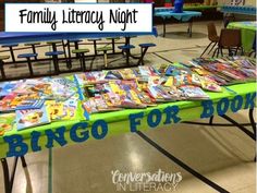 a green table topped with lots of children's books next to a blue sign that says family library night