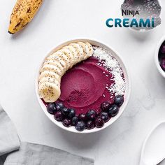 a bowl filled with blueberries and bananas next to two bowls full of ice cream