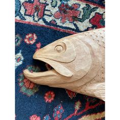 a wooden fish on a rug with it's mouth open