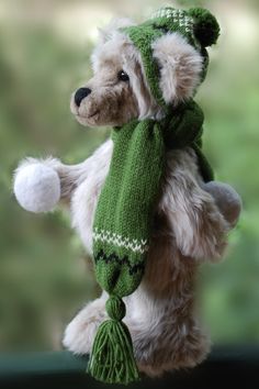 a teddy bear wearing a green scarf and hat with pom - poms on it