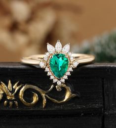 a ring with a heart shaped emerald surrounded by diamonds