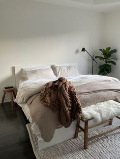 a bed with blankets and pillows on top of it in a bedroom next to a window