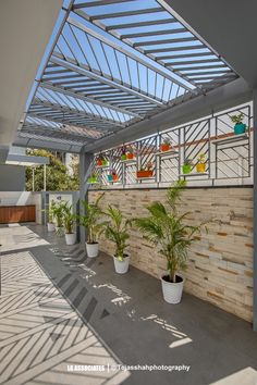 an outdoor patio with potted plants on the wall and sun shining through the roof