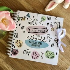 a notebook with the words, one year in the world written on it next to a pink flower