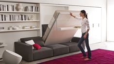 a woman standing in front of a couch that is open