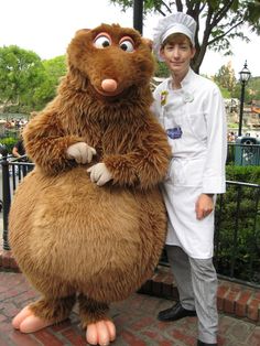 a man in a chef's outfit standing next to a giant stuffed animal character