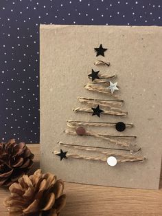 a christmas tree made out of driftwood and stars on the front is displayed next to a pine cone