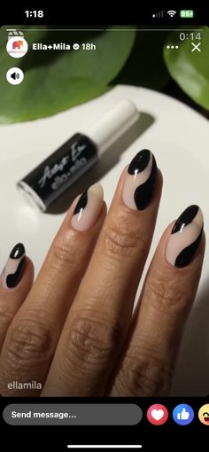 a woman's hand with black and white nail polish on top of her nails