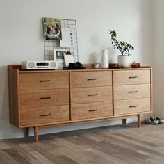 a wooden dresser sitting on top of a hard wood floor next to a white wall