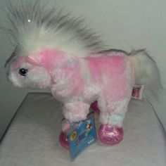 a stuffed pony with pink shoes on top of a bed