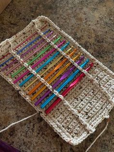 a crocheted basket with many colored toothbrushes in it on a table