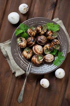 a plate full of snails and garlic on a wooden table