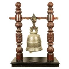 an antique bell is on top of a wooden stand with two bells attached to it