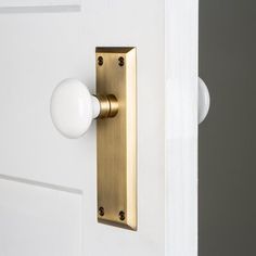 a white door with a gold handle and a light bulb on it's side