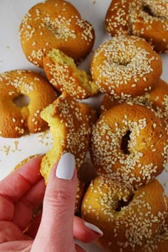 a hand is picking up some sesame seed bagels