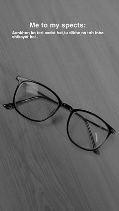 a pair of black glasses sitting on top of a wooden table next to an advertisement for eyeglasses