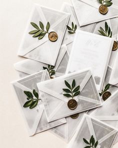 some white envelopes with green leaves on them and one gold coin in the middle