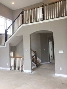 an empty living room with stairs leading up to the second floor and another open door