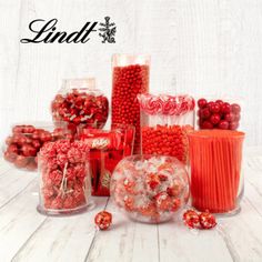 there are many candies and candy in the glass vases on the white table