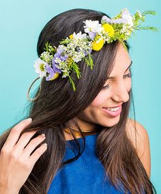 a woman with long hair wearing a flower crown on her head and smiling at the camera