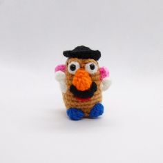 a small crocheted bird with a black hat on its head and pink cheeks