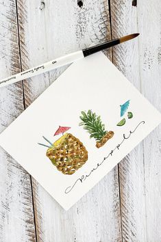 a piece of paper with pineapples on it next to a paintbrush and watercolor pencil