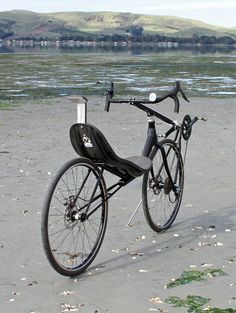 a black bike parked on top of a sandy beach