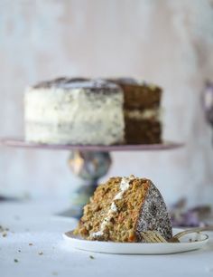 a slice of carrot cake on a plate with the rest of the cake in the background