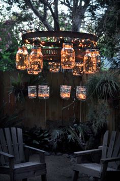 mason jar chandelier with lights hanging from it's sides in the backyard