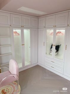 an empty room with white cabinets and pink chairs