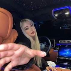 a woman sitting in the driver's seat of a car with her hand on the steering wheel