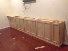 an empty room with unfinished cabinets and wires on the wall