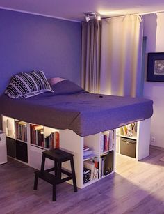 a bed that is in the middle of a room with bookshelves underneath it