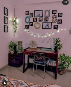 a room with pictures on the wall and a desk in front of it, surrounded by potted plants