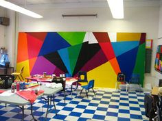 a man standing in front of a brightly colored wall with lots of chairs around it