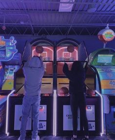 two people standing next to each other in front of some arcade machines with neon lights