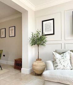 a living room filled with furniture and pictures hanging on the wall above it's doorway