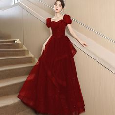 a woman in a red dress standing on some stairs