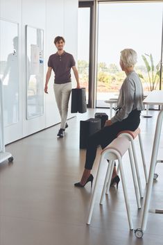 a woman sitting on top of a white chair next to a man in a black shirt