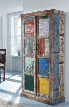 an old wooden cabinet is painted multicolored and has many signs on the doors