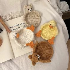 four crocheted ducks are sitting on a bed next to a book and pen