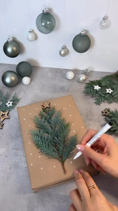 someone is making a christmas tree out of wrapping paper and twine of baubles